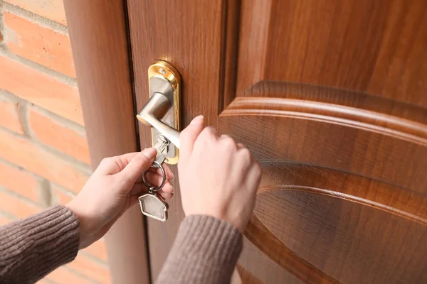 Femme avec clé ouvrant porte d'entrée, gros plan — Photo