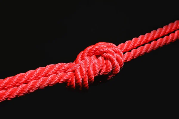 Corda vermelha com nó no fundo preto — Fotografia de Stock