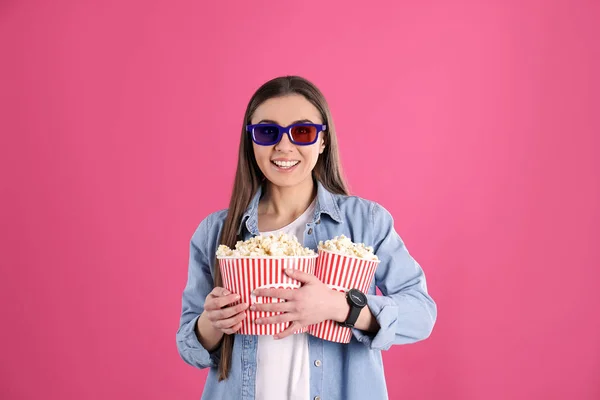 Junge Frau mit 3D-Gläsern und leckerem Popcorn auf farbigem Hintergrund — Stockfoto
