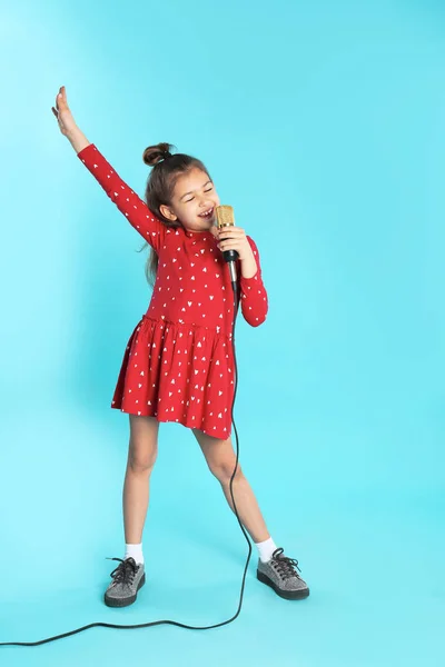 Χαριτωμένο αστείο κορίτσι με μικρόφωνο στο χρώμα φόντου — Φωτογραφία Αρχείου