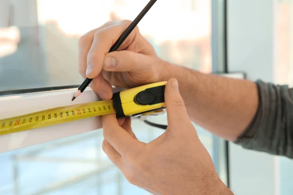 Service man meten venster voor installatie binnenshuis, close-up — Stockfoto