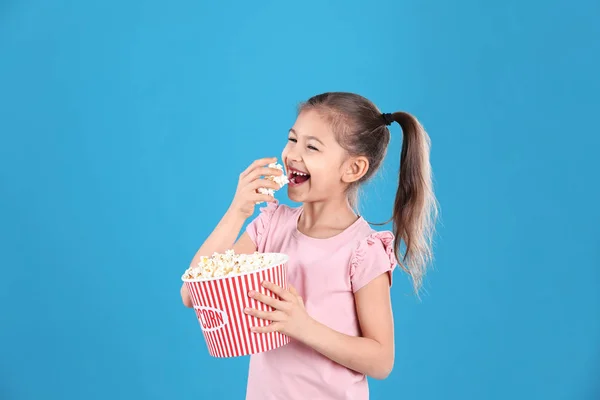 Linda niña con palomitas de maíz en el fondo de color —  Fotos de Stock