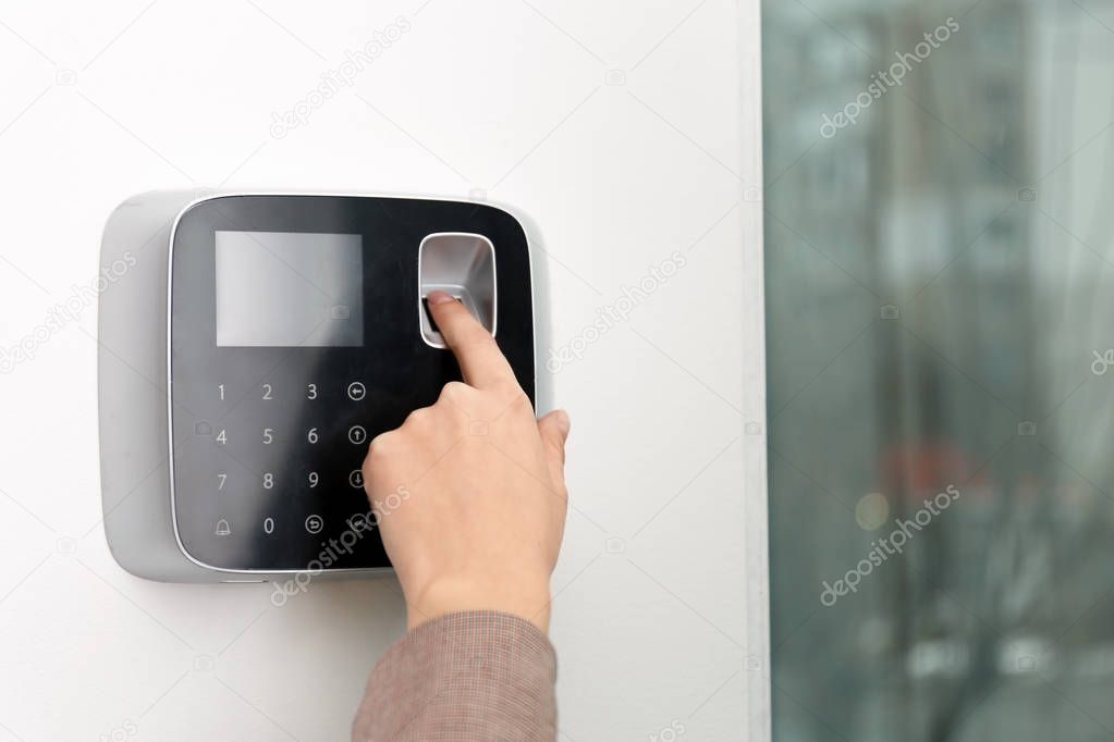 Woman scanning fingerprint on alarm system indoors, closeup. Space for text