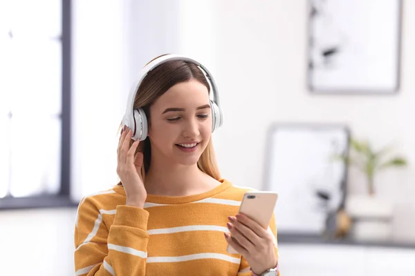 Девочка-подросток слушает музыку в наушниках на размытом фоне — стоковое фото