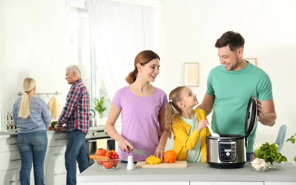 Keluarga bahagia menyiapkan makanan dengan multi kompor modern di dapur — Stok Foto