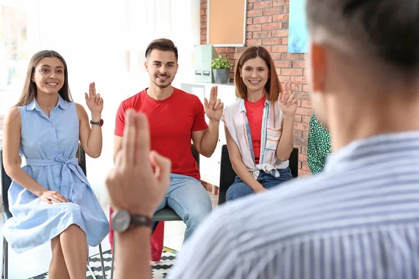 Grupo de jóvenes que aprenden el lenguaje de señas con el profesor en interiores — Foto de Stock