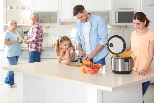 Счастливая семья готовит еду с современной мультиваркой на кухне — стоковое фото