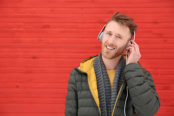 Jeune homme écoutant de la musique avec des écouteurs contre le mur de couleur. Espace pour le texte — Photo