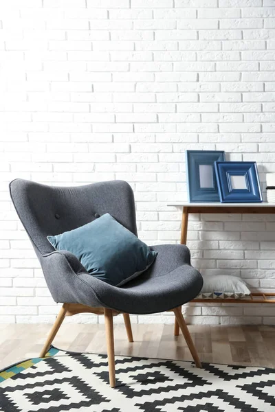 Intérieur moderne avec fauteuil confortable et table près du mur de briques — Photo