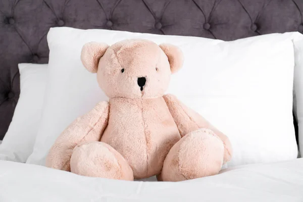 Niedlicher Teddybär sitzt drinnen im Bett — Stockfoto