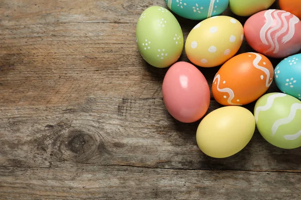 Muchos huevos de Pascua pintados de colores sobre fondo de madera, vista superior. Espacio para texto —  Fotos de Stock