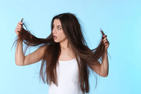 Känslomässiga kvinna med skadat hår färg bakgrunden. Kluvna toppar — Stockfoto