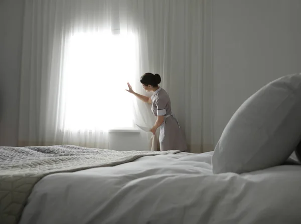 若いメイドホテルの部屋でカーテンを開ける — ストック写真