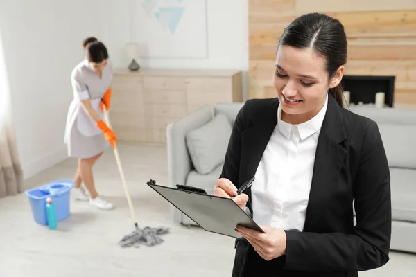 Gerente de limpeza verificando o trabalho de empregada doméstica no quarto do hotel — Fotografia de Stock