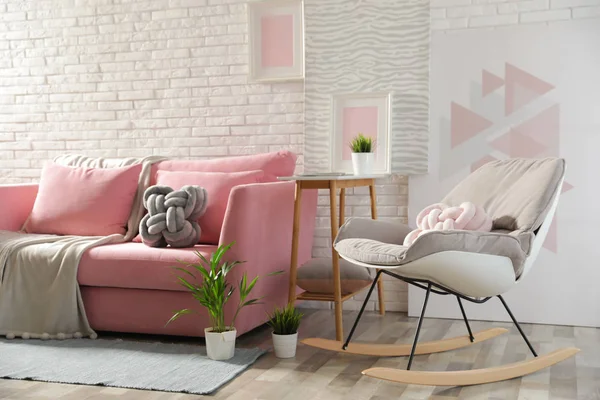 Elegante salón interior con sofá y sillón mecedora cerca de la pared de ladrillo — Foto de Stock