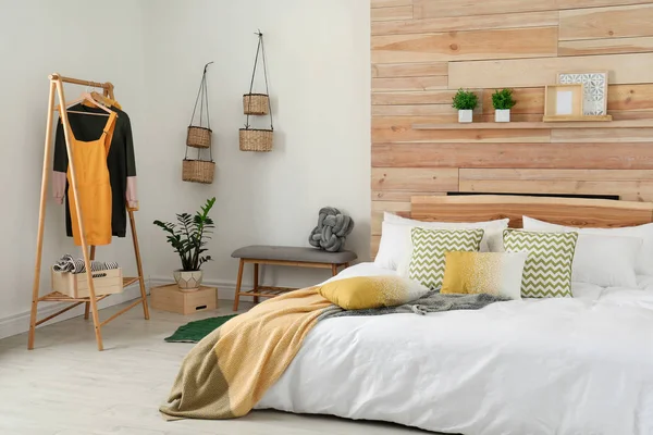 Quarto elegante interior com cama confortável perto da parede de madeira — Fotografia de Stock