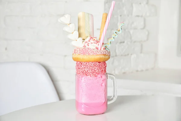 Välsmakande milkshake med godis i mason jar på bord på café — Stockfoto