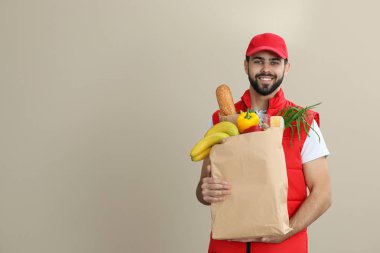 Kesekağıdı rengi arka plan, metin için yer üzerinde taze ürünlerle tutan adam. Gıda dağıtım hizmeti