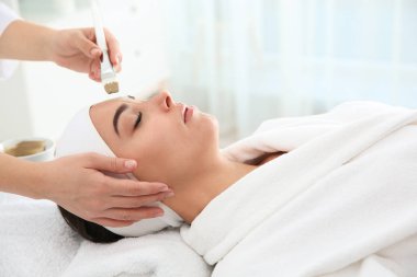 Spa salonu müşterinin yüzüne maske uygulayarak güzellik uzmanı