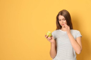 Hassas dişler ve apple renk arka plan üzerinde duygusal genç kadınla. Metin için yer