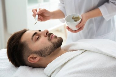 Spa salonu müşterinin yüzüne maske uygulayarak güzellik uzmanı