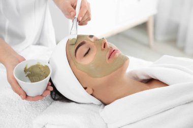 Spa salonu müşterinin yüzüne maske uygulayarak güzellik uzmanı