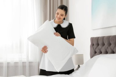Genç hizmetçi otel odasında yatak yapma