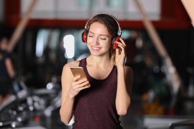 Genç kadın kulaklıklarla müzik üstünde hareket eden aygıt vasıl jimnastik salonu
