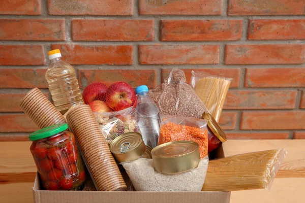 Caixa de doação com comida na mesa perto da parede de tijolo — Fotografia de Stock