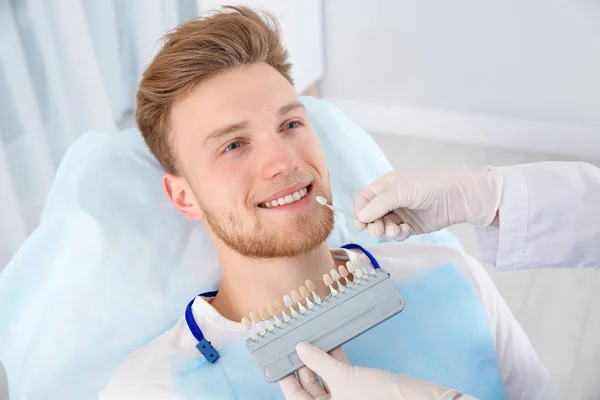Zahnarzt wählt Zahnfarbe des Patienten mit Palette in Klinik aus — Stockfoto