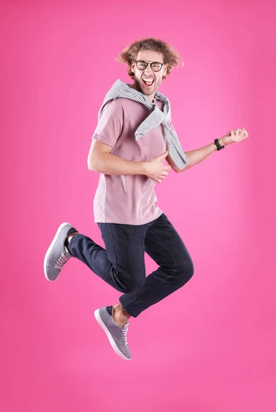 Junger Mann spielt Luftgitarre auf farbigem Hintergrund — Stockfoto