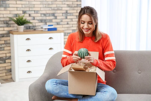 Ung kvinna öppning skifte på soffan i vardagsrummet — Stockfoto