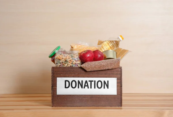 Caja de donación con comida en la mesa sobre fondo claro — Foto de Stock