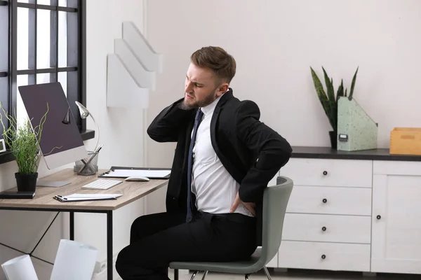 Empresario que sufre dolor de espalda en el lugar de trabajo —  Fotos de Stock