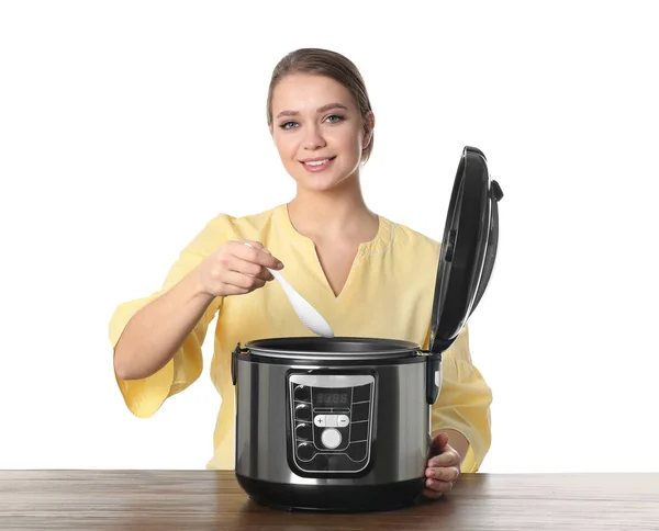 Jovem mulher preparando comida com multi fogão moderno à mesa contra fundo branco — Fotografia de Stock