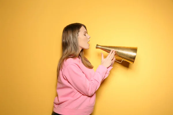 Mladá žena s megafonem na barevném pozadí — Stock fotografie