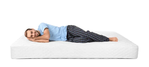 Young man lying on mattress against white background — Stock Photo, Image