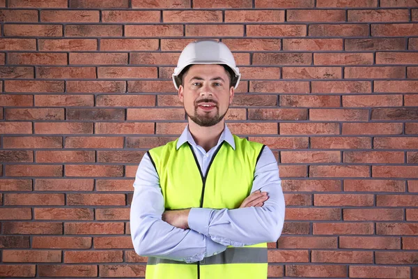 Ingeniero industrial masculino en uniforme sobre fondo de pared de ladrillo. Equipo de seguridad — Foto de Stock