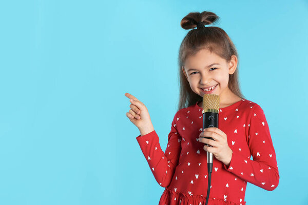 Cute funny girl with microphone on color background. Space for text