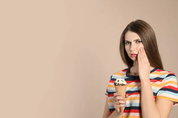 Emotional young woman with sensitive teeth and ice cream on color background. Space for text — Stock Photo, Image