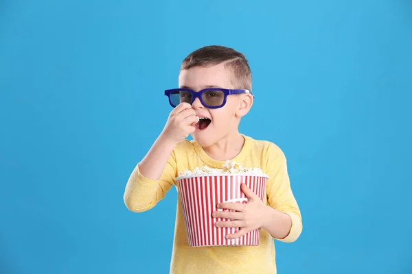 Милий маленький хлопчик з попкорном і окулярами на кольоровому фоні — стокове фото