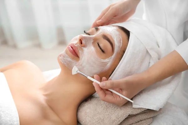 Cosmetologue appliquant un masque sur le visage du client dans le salon de spa — Photo