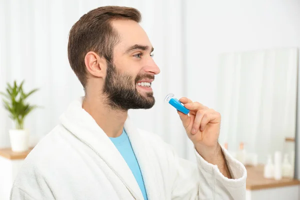 Young man using teeth whitening device at home — Stock Photo, Image