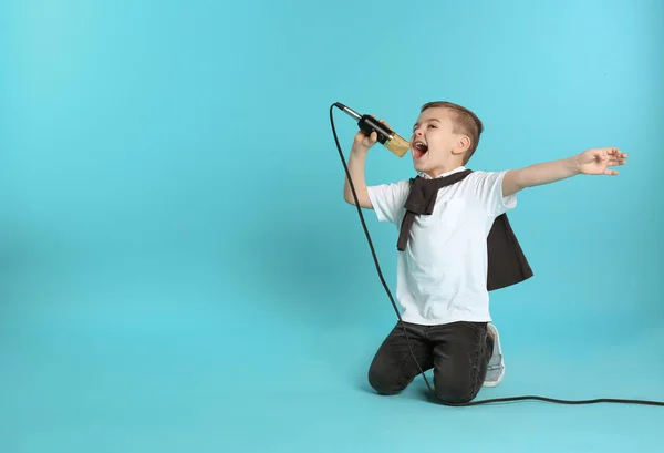 Söt rolig pojke med mikrofon på färgbakgrund. Utrymme för text — Stockfoto