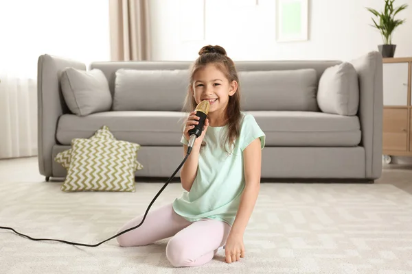 Χαριτωμένο αστείο κορίτσι με το μικρόφωνο στο σαλόνι — Φωτογραφία Αρχείου