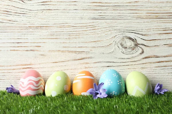 Coloridos huevos de Pascua pintados con flores sobre hierba verde sobre fondo de madera, espacio para texto —  Fotos de Stock