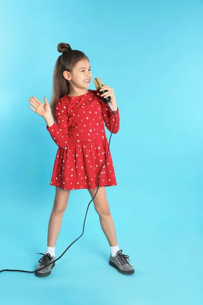 Χαριτωμένο αστείο κορίτσι με μικρόφωνο στο χρώμα φόντου — Φωτογραφία Αρχείου