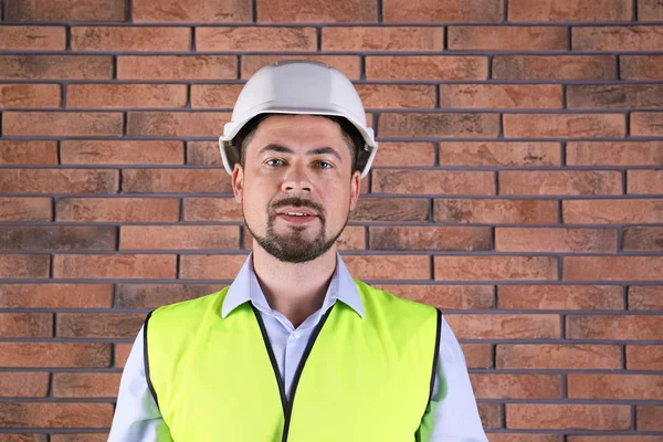 Ingeniero industrial masculino en uniforme sobre fondo de pared de ladrillo. Equipo de seguridad —  Fotos de Stock