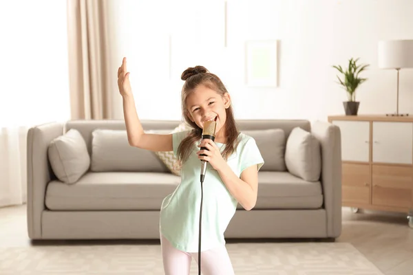 Menina engraçada bonito com microfone na sala de estar — Fotografia de Stock