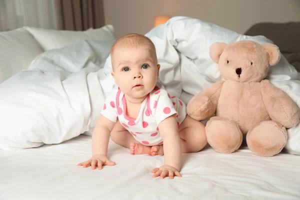 Niedliche Baby-Mädchen mit Spielzeug auf dem Bett zu Hause. Schlafenszeit — Stockfoto